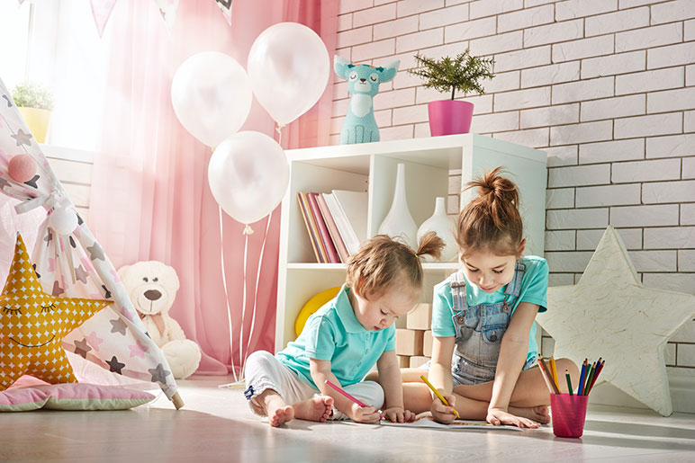 Two young Montessori children drawing at home on the floor. 