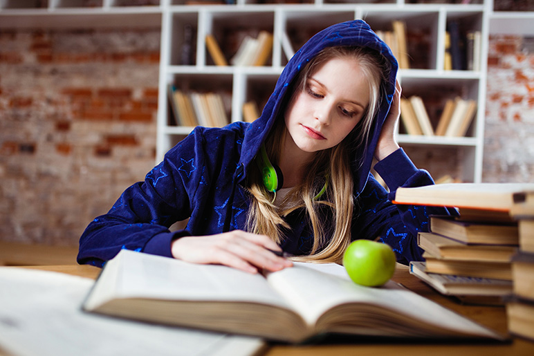 A teenager reading, homeschool vs. public school pros and cons